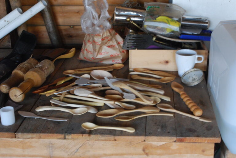 Hand-carved wooden spoons made from whittling, laid out on a workbench
