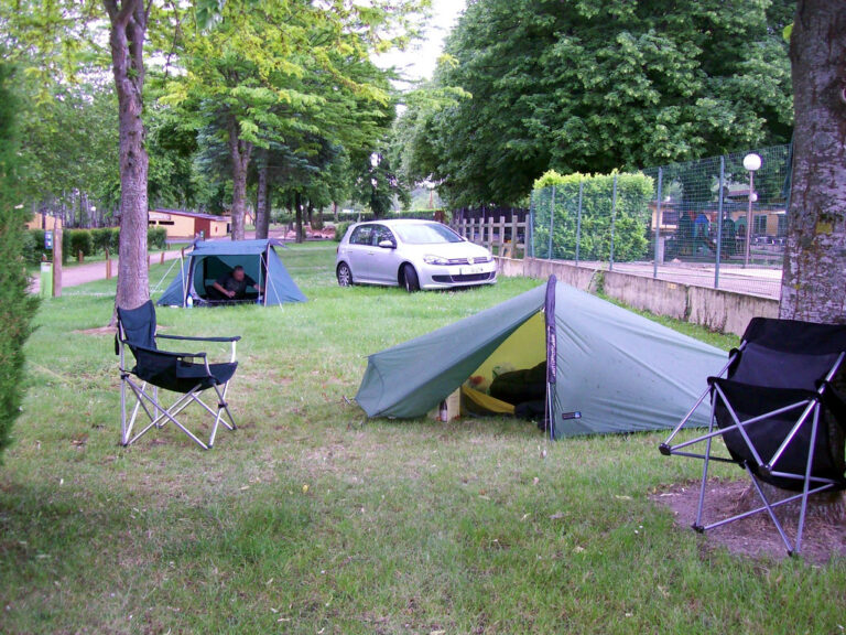 Dome tents pitched at a campsite with folding chairs set up nearby