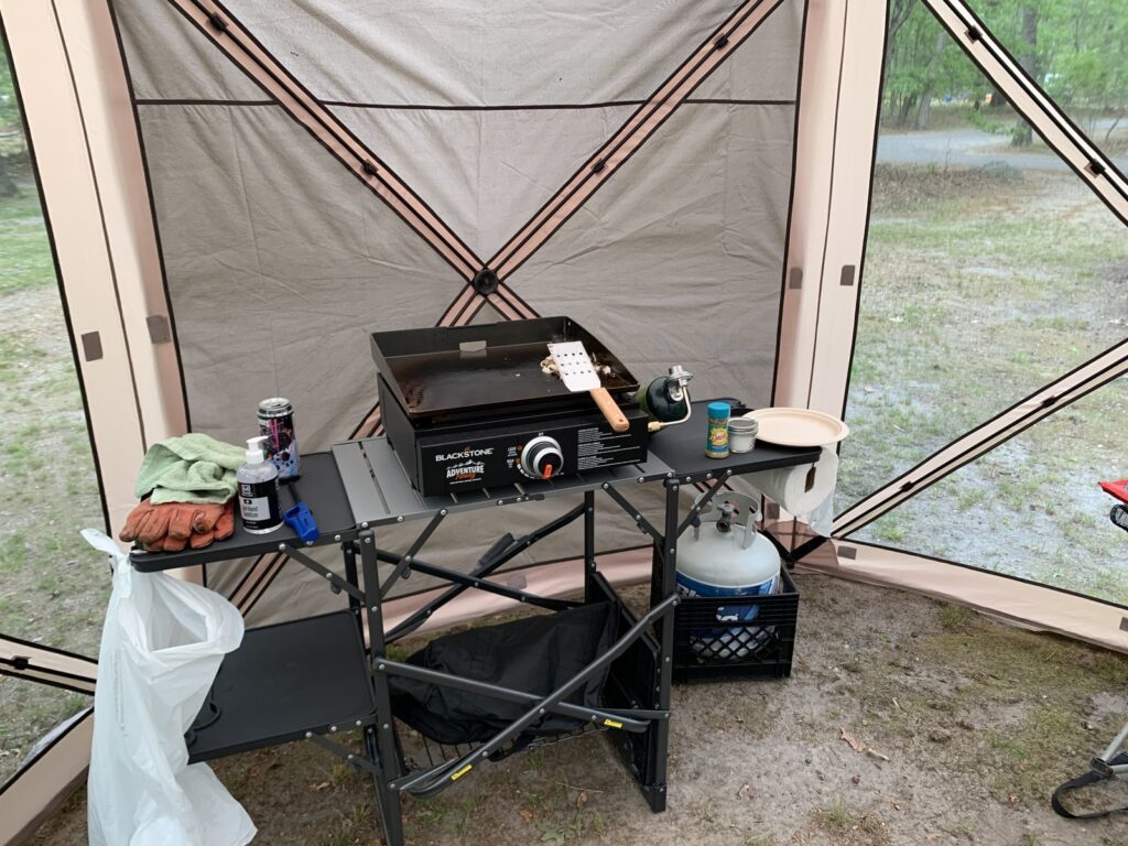 The Blackstone Adventure Ready 17-inch griddle set up tabletop-only on a folding camp table inside a screen tent